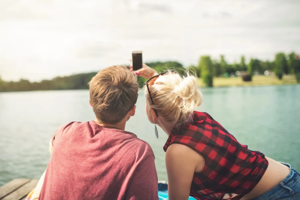 WhatsFlirt Review - a guy and a girl taking selfies by the lake