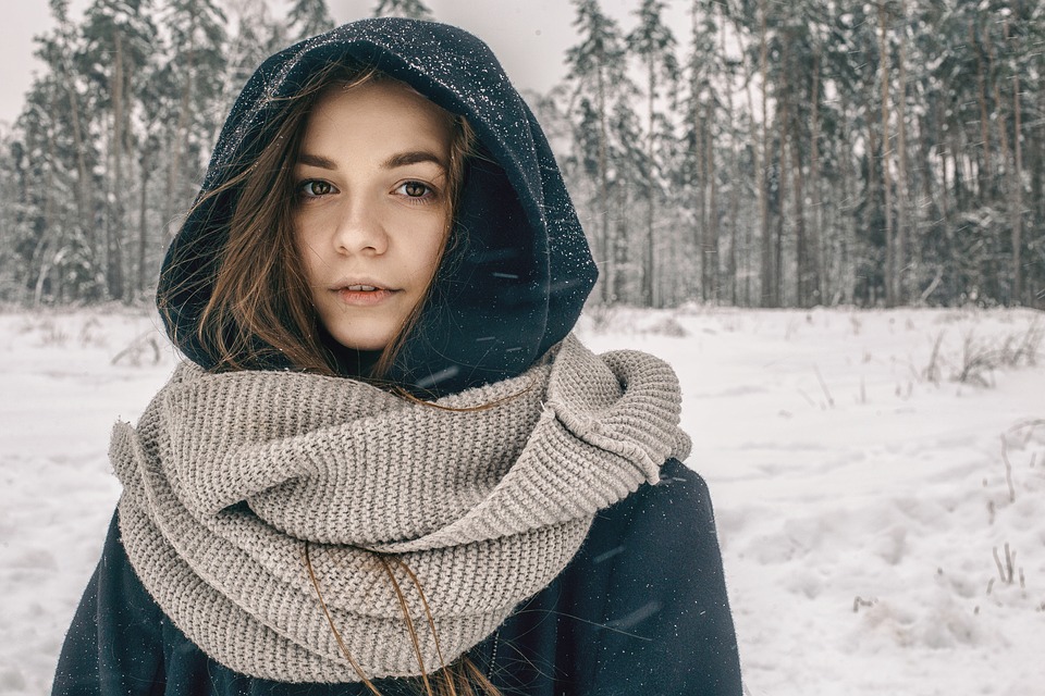 Hooded girl walking through a snow-covered forest