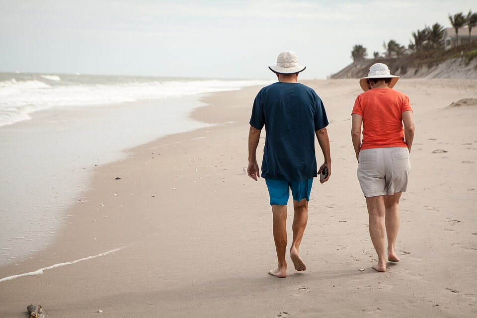 Old people in love walking on the beach